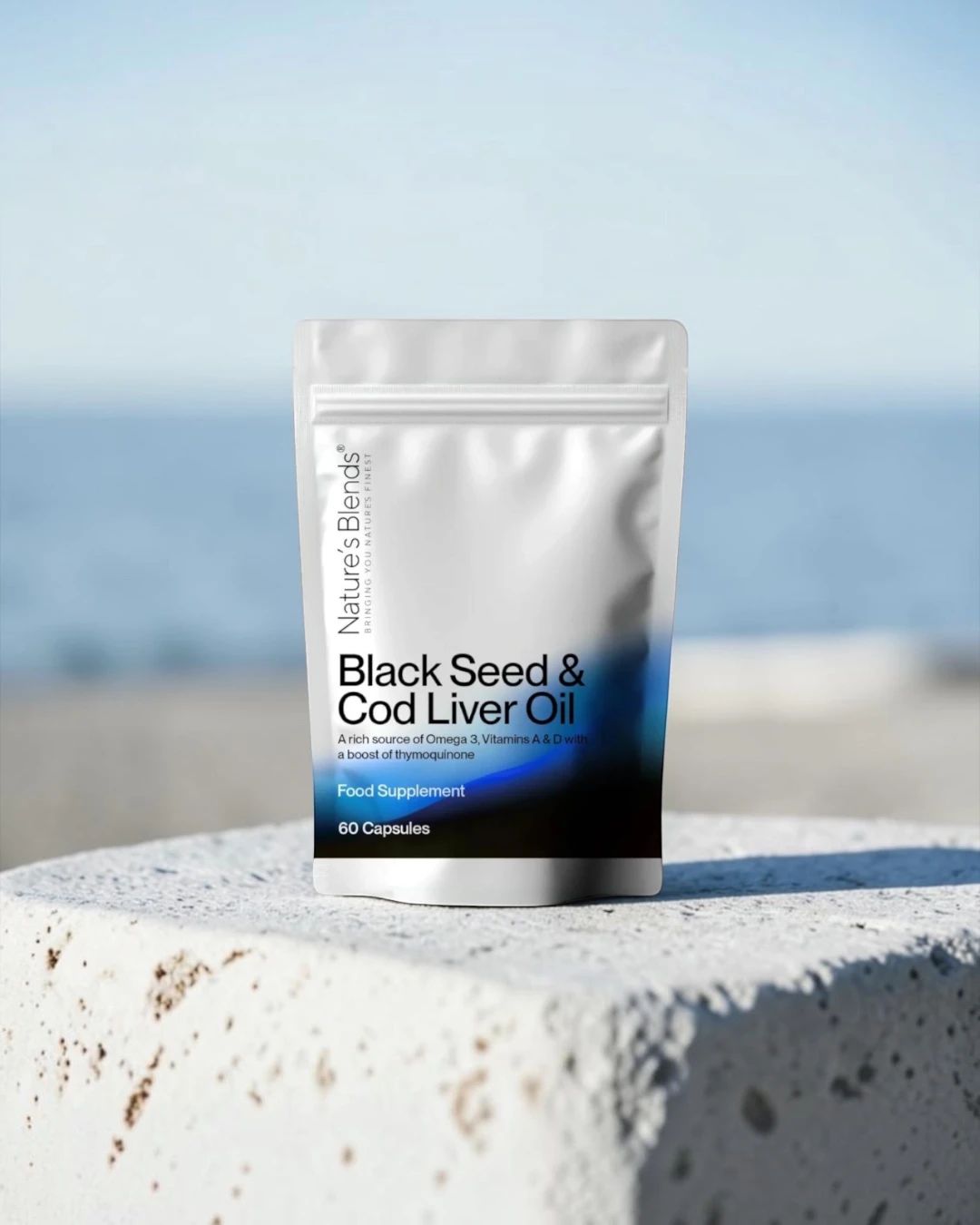 A pouch of Nature's Blends Black Seed & Cod Liver Oil capsules on a stone block by the sea